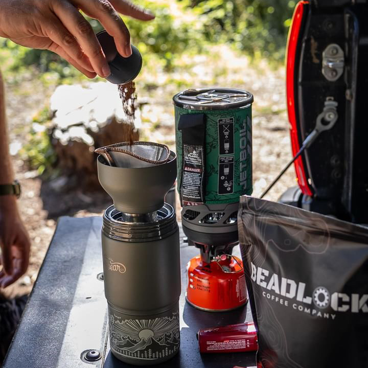 Making pour-over coffee with an Adventure Flask at an outdoor table.