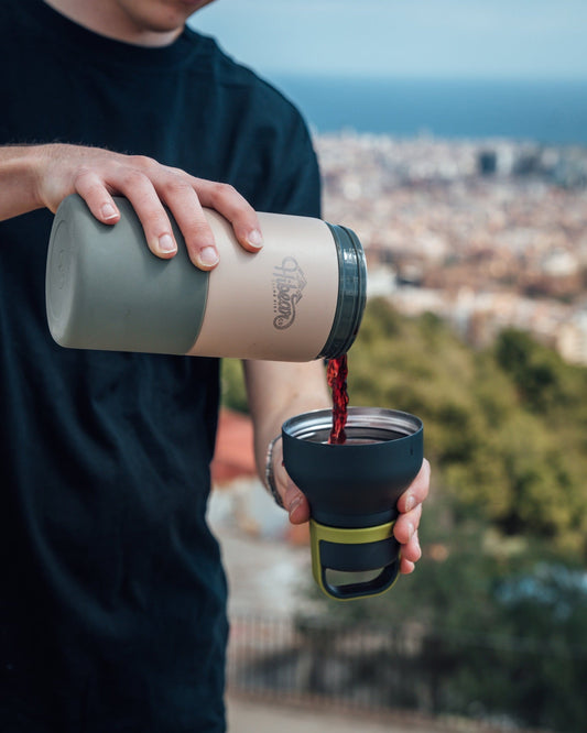 Pouring a red drink from an Adventure Flask into its serving cup outdoors.
